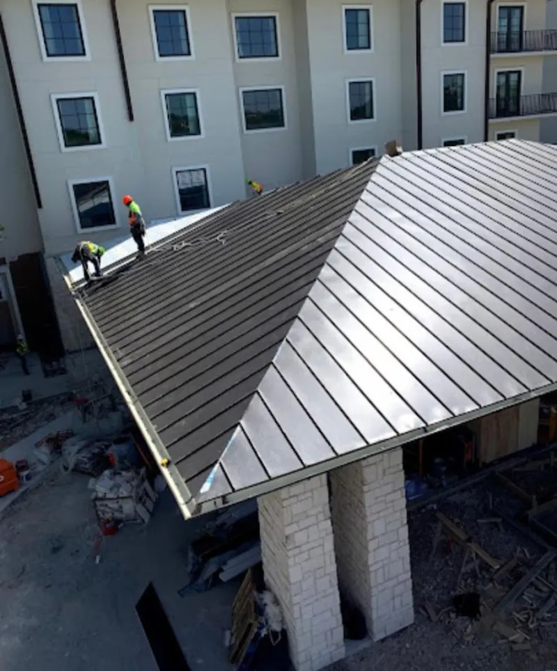 Crew installing standing seam metal roof panels on a commercial project in Riviera Beach
